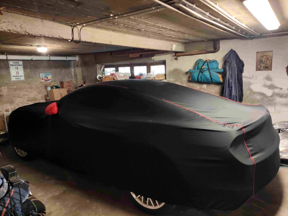 Ford Mustang parked in a garage, protected with a black car cover from Cover Company